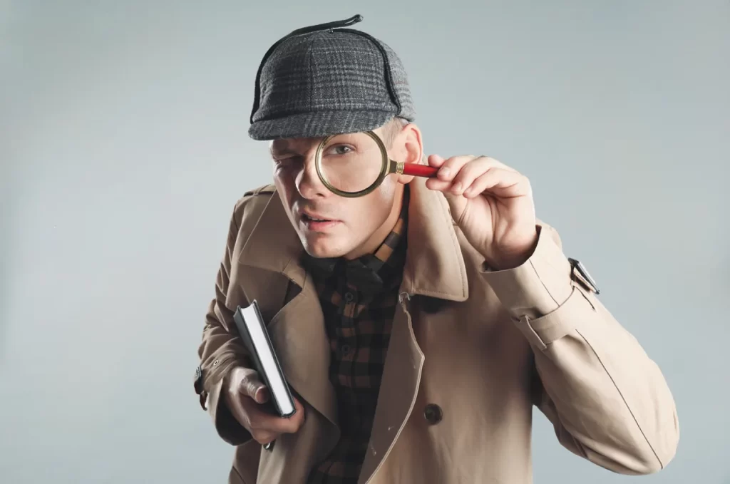 A detective holding up a magnifying glass to his eye