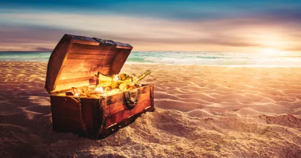 an open treasure chest sitting on a sandy beach at sunset